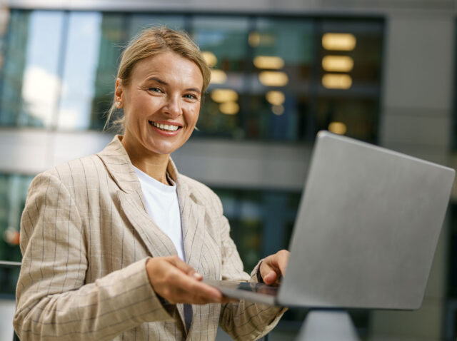 smiling-female-freelancer-working-laptop-on-modern-2024-10-18-08-10-48-utc