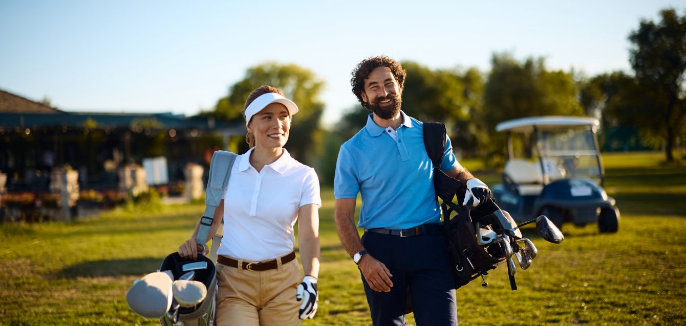 Happy golf partners walking to the next hole on the court.