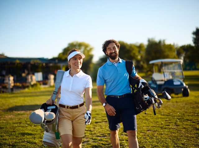 Happy golf partners walking to the next hole on the court.