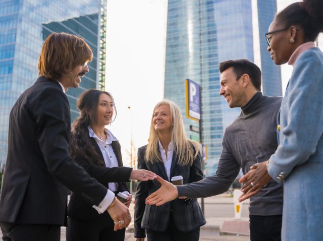 Group of multi-ethnic business people in a business park introducing themselves and shaking hands outdoors